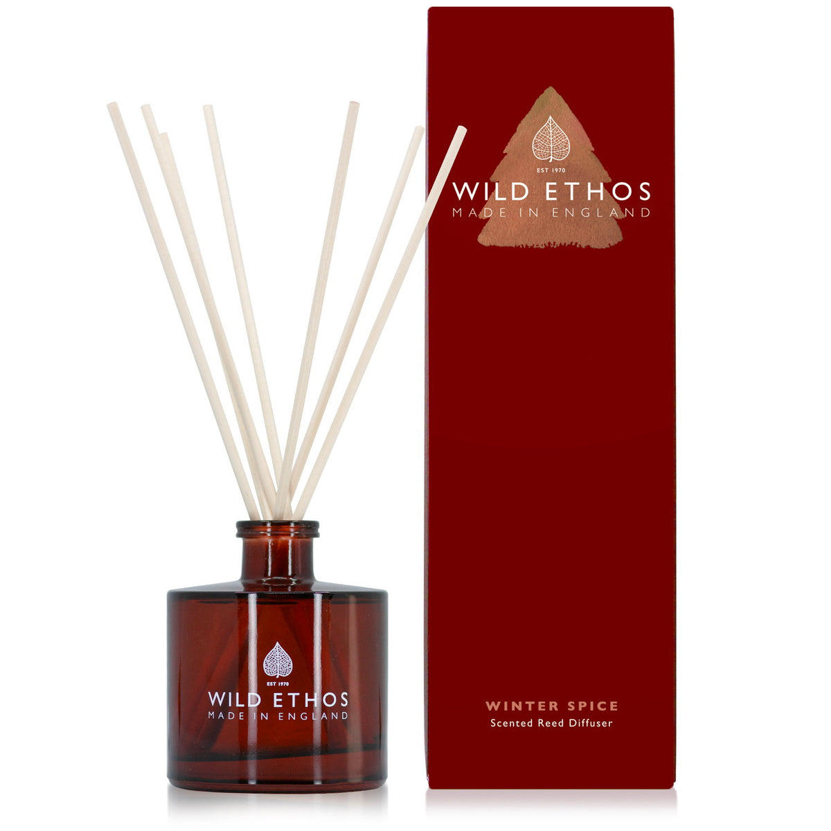 Wild Ethos Winter Spice scented reed diffuser in an amber glass bottle with reeds, beside its tall red gift box