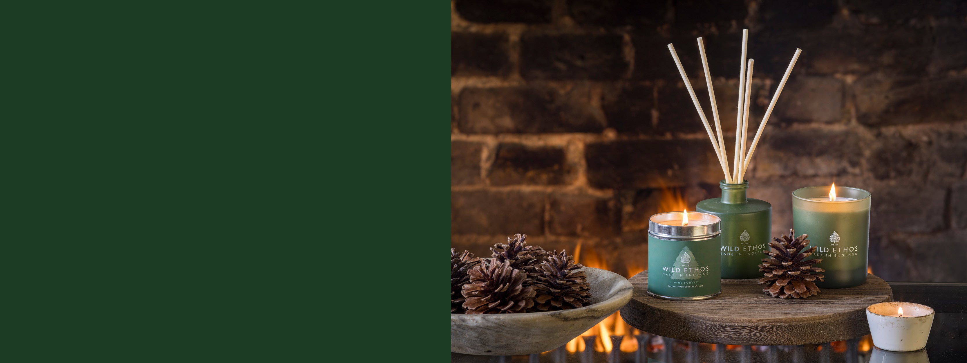 Candles and a diffuser on a stone surface with a fireplace in the background